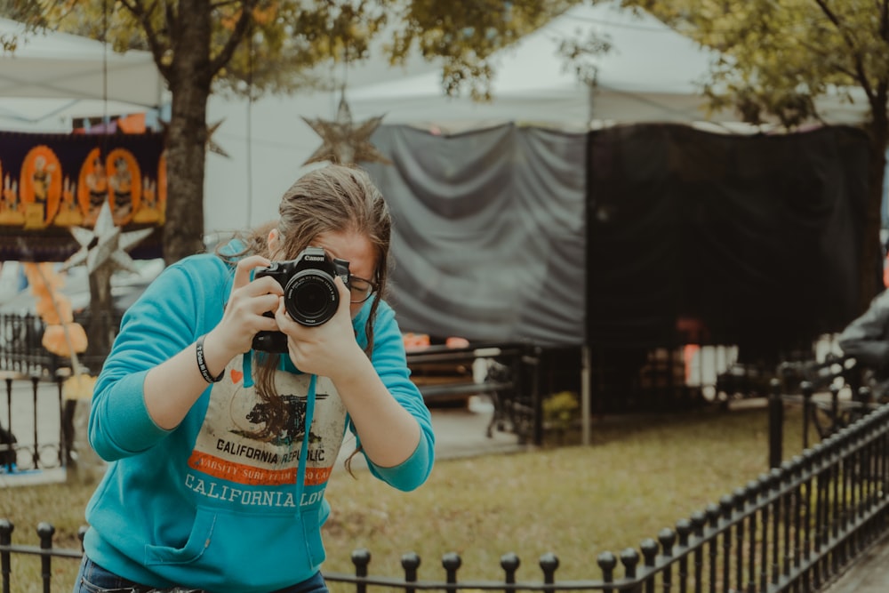 woman in blue t-shirt holding black dslr camera