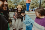 woman in gray sweater smiling beside girl in blue jacket