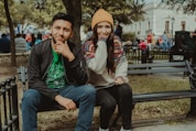 man in gray hoodie and blue denim jeans sitting on bench