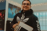 man in black and white hoodie holding white tablet computer