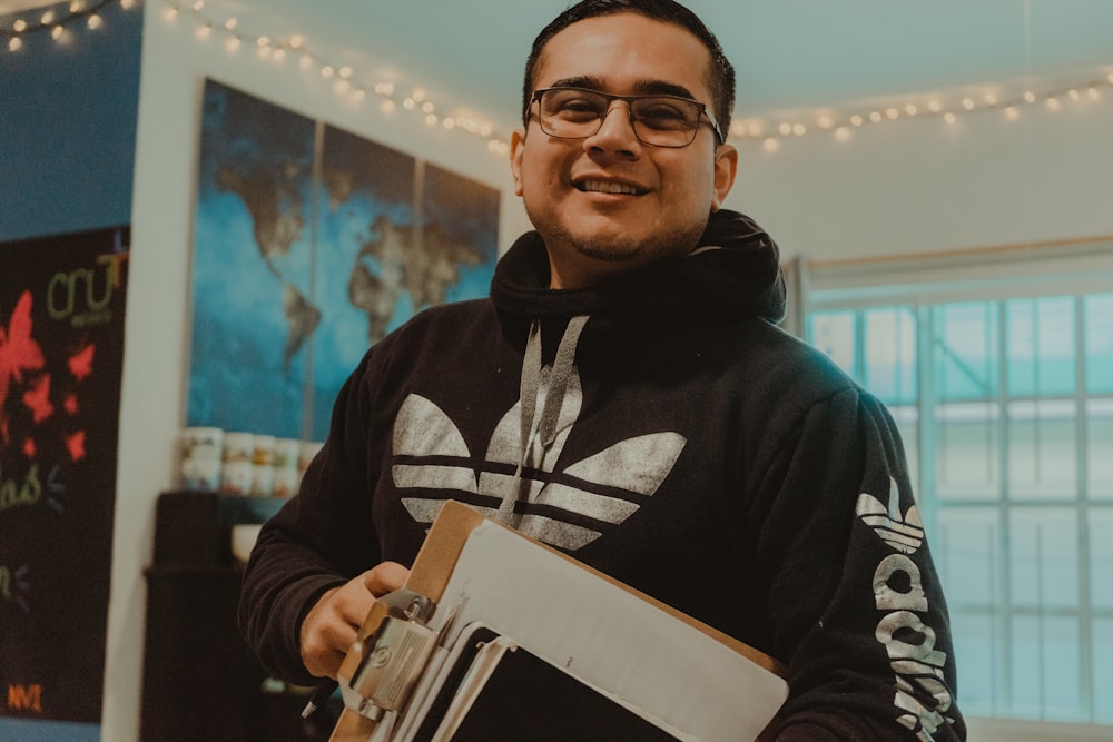 man in black and white hoodie holding white tablet computer