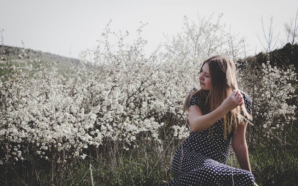 낮 동안 푸른 잔디밭에 앉아 흑백 물방울 무늬 드레스를 입은 여자
