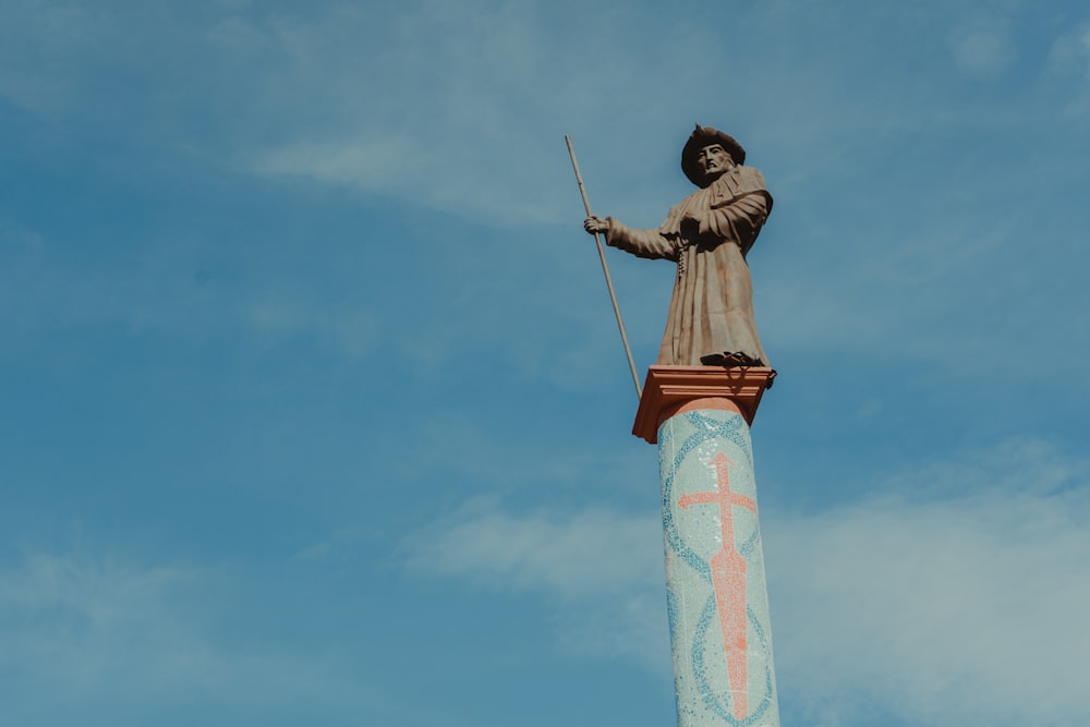 homem na camisa social marrom e calças marrons segurando estátua do pau