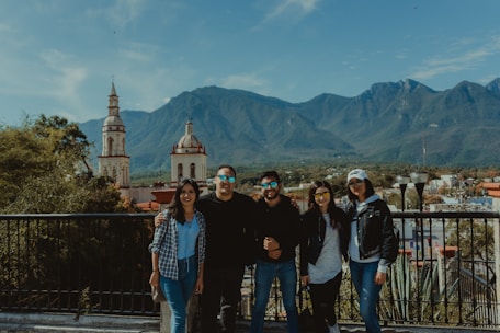 A group of happy travelers enjoying a scenic sightseeing tour with mountains in the background.