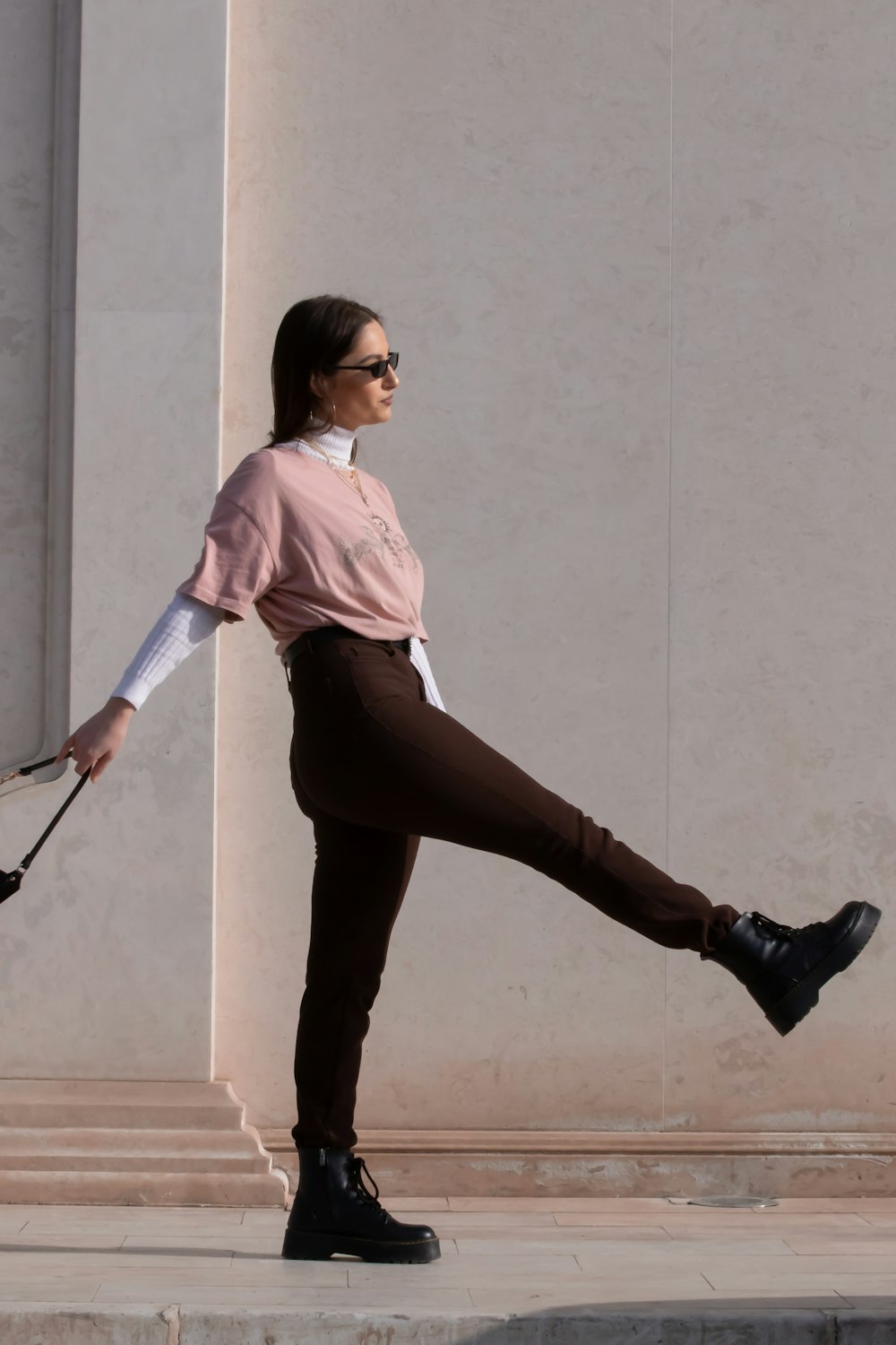 donna in camicia rosa e pantaloni neri che tiene bastone da passeggio