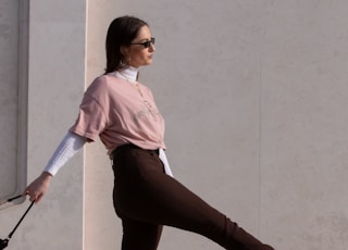 woman in pink shirt and black pants holding walking stick