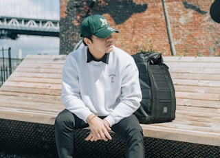 man in white dress shirt and black pants sitting on brown wooden bench during daytime