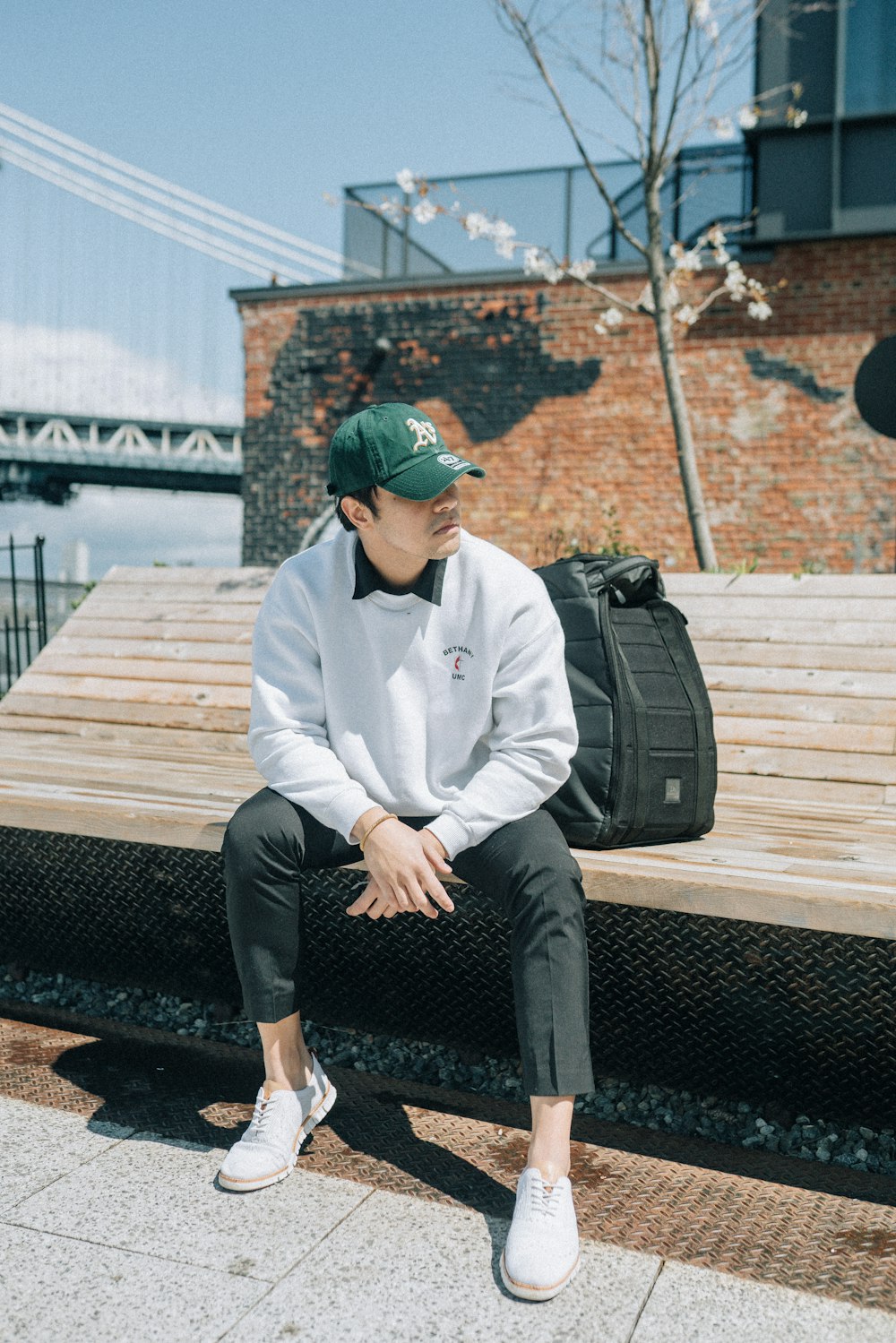 man in white dress shirt and black pants sitting on brown wooden bench during daytime