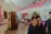 A colorful indoor setting with a vividly decorated ice cream shop. Bright pink and yellow walls with hanging lanterns, refrigerated counters, and a cart with a pink canopy. Two people are present, one in the foreground adjusting sunglasses, and another partially visible in the background.