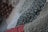 A close-up view of a quilt with various floral patterns. The dominant green fabric features small flowers in yellow and white, with hints of red and blue. The quilt appears textured and soft, indicating the presence of stitching and potentially hand-made craftsmanship.