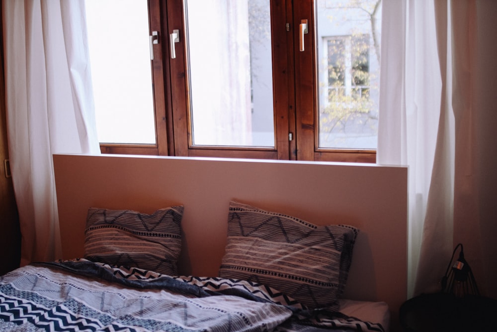 Cadre de lit en bois marron avec linge de lit gris et blanc