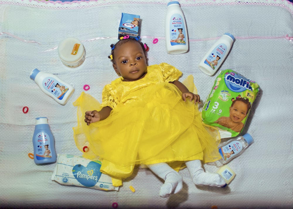 baby in yellow dress lying on bed