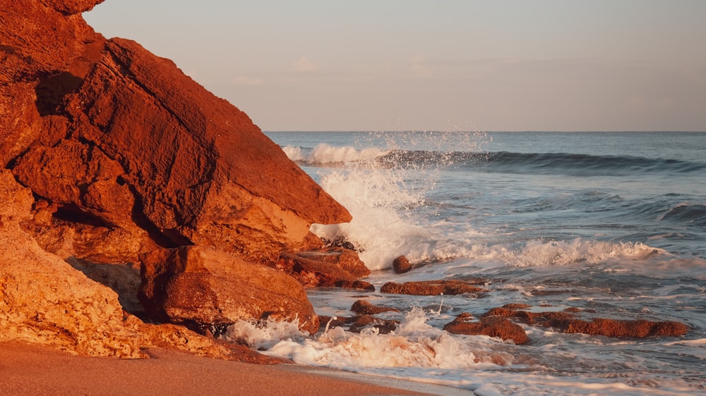 formação rochosa marrom perto do mar durante o dia
