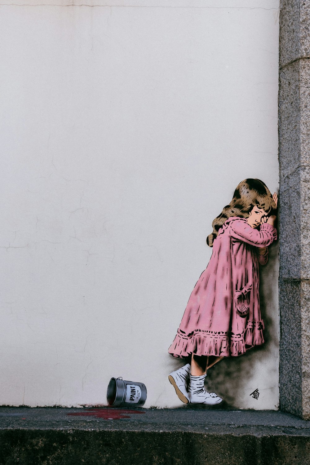 girl in pink dress leaning on wall