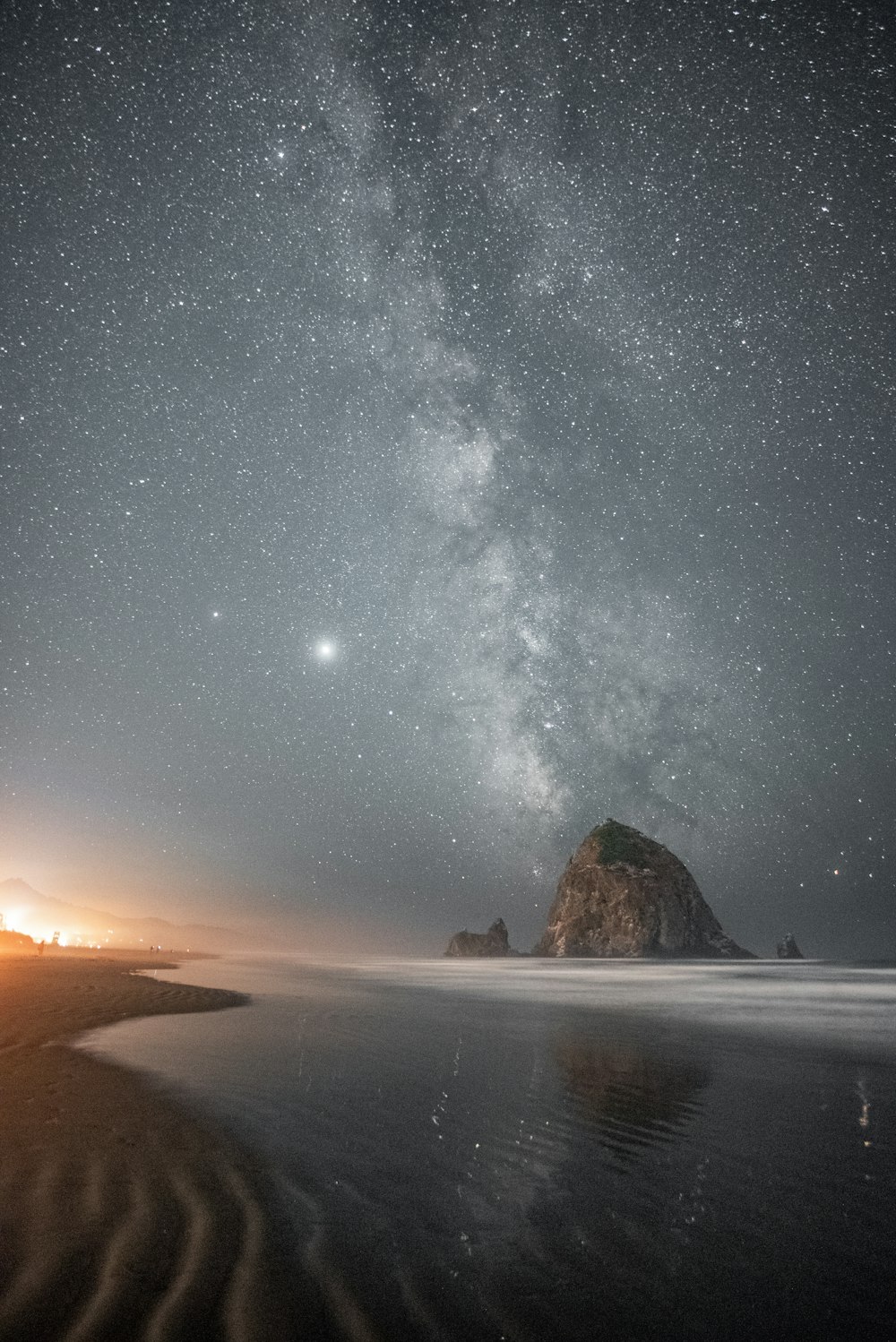 Formación rocosa marrón en la orilla del mar bajo una noche estrellada