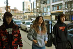 A group of young people wearing urban style custom t-shirts, laughing and walking in the city.