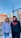 Two young individuals stand outdoors in an urban setting, both wearing hoodies with the text 'YOUNG CREATIVE EST. 2020' printed on them. The background showcases buildings, a street, and a clear blue sky. A woman wears a gray hoodie and jeans, and a man wears a black hoodie and black pants.