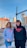 Two young individuals stand outdoors in an urban setting, both wearing hoodies with the text 'YOUNG CREATIVE EST. 2020' printed on them. The background showcases buildings, a street, and a clear blue sky. A woman wears a gray hoodie and jeans, and a man wears a black hoodie and black pants.
