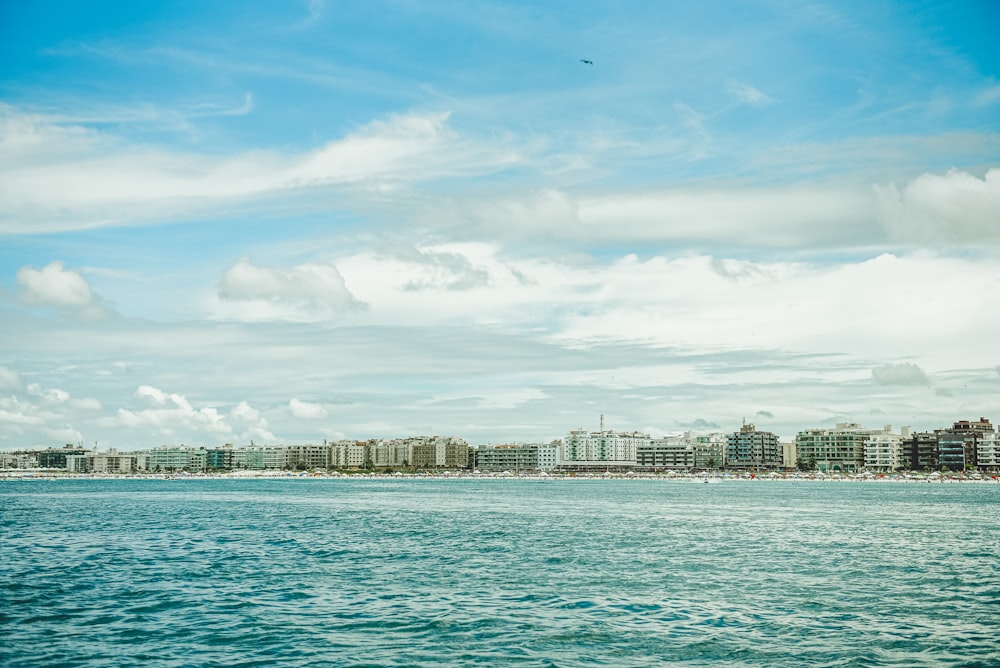 city skyline across body of water under blue and white sunny cloudy sky during daytime