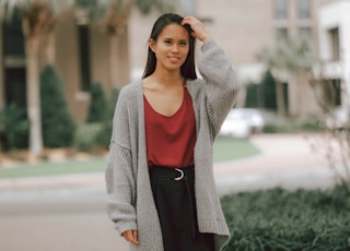 woman in gray cardigan standing on gray concrete pathway during daytime