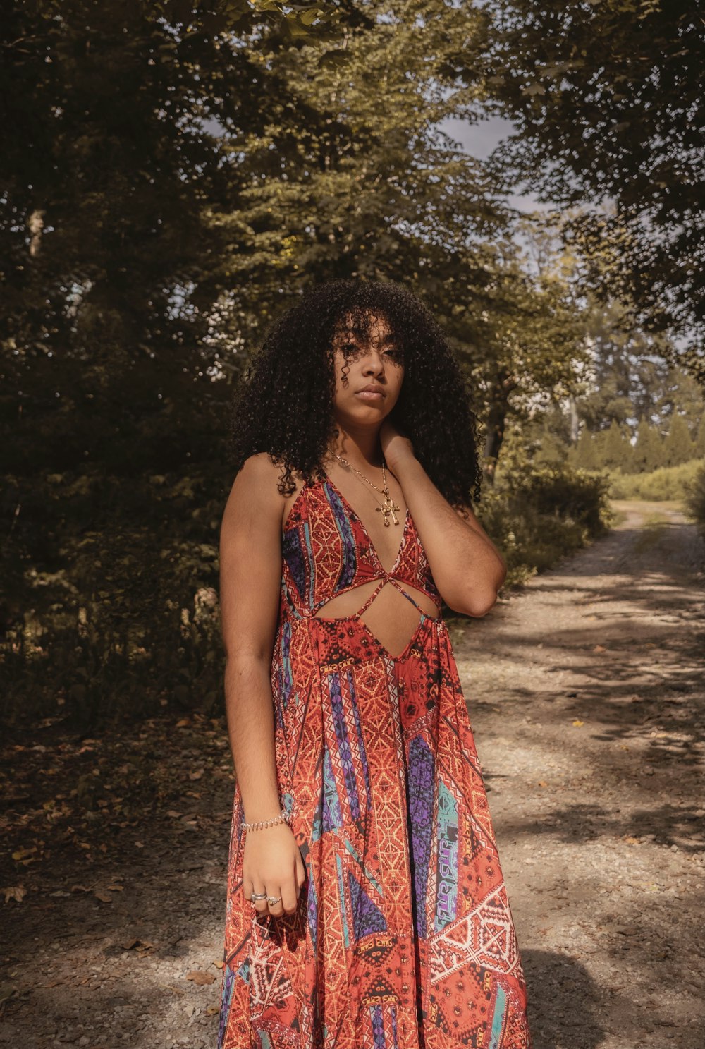 woman in blue and red floral halter top dress standing on brown dirt road during daytime