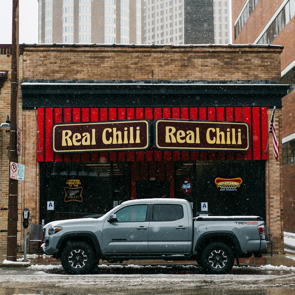 white crew cab pickup truck parked beside brown building during daytime