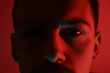 Close-up shot of a provider's eyes, teasing with a hint of mystery and allure, framed by soft red lighting.