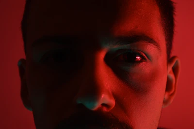 Close-up shot of a provider's eyes, teasing with a hint of mystery and allure, framed by soft red lighting.