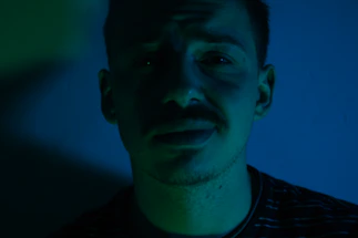 A moody, cinematic portrait of Diego R. Fernandez with dramatic lighting and a dark green background.