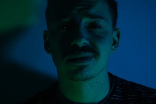 A moody, cinematic portrait of Diego R. Fernandez with dramatic lighting and a dark green background.