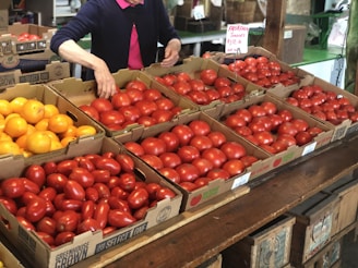 Stacks of freshly harvested tomatoes and peppers arranged neatly on a market stall