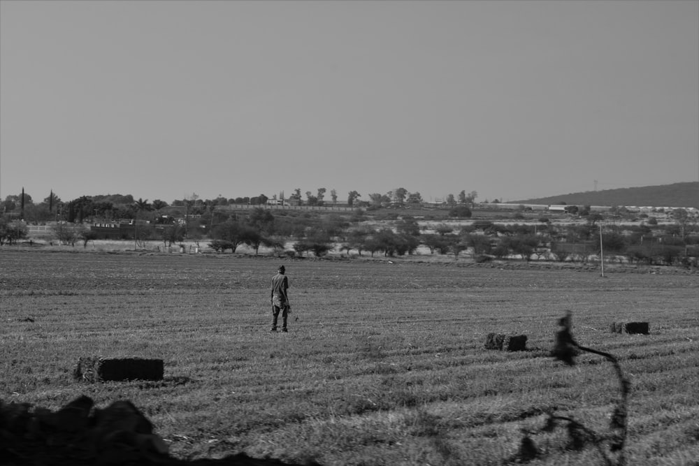 grayscale photo of man walking on grass field