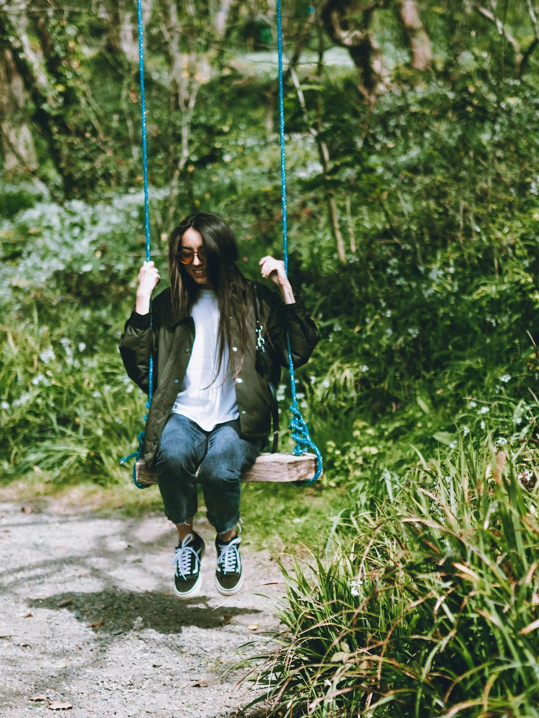 woman in gray long sleeve shirt sitting on blue swing during daytime