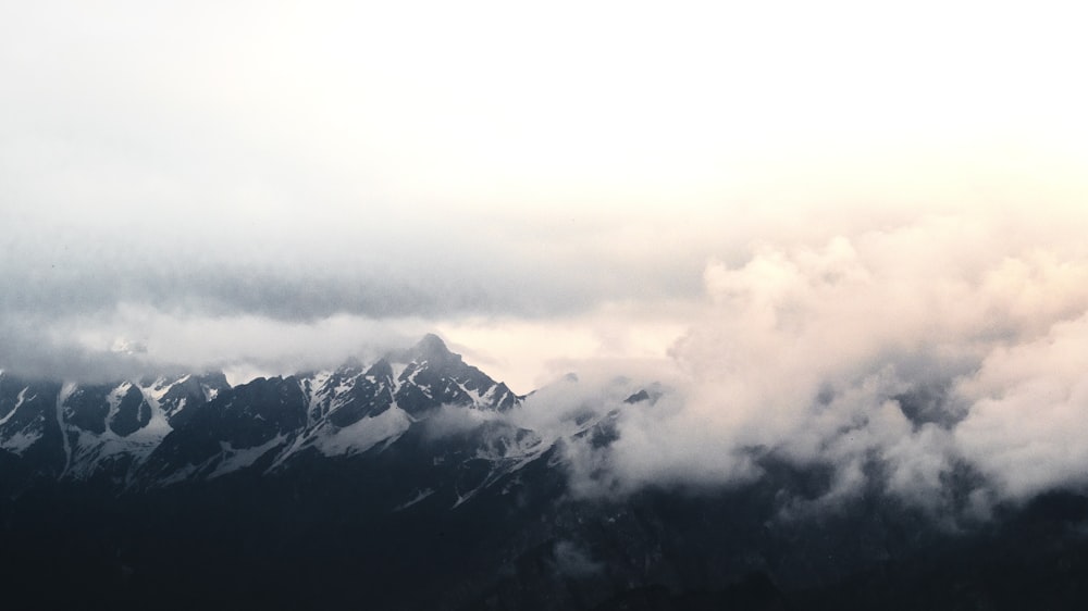 snow covered mountain under white clouds during daytime