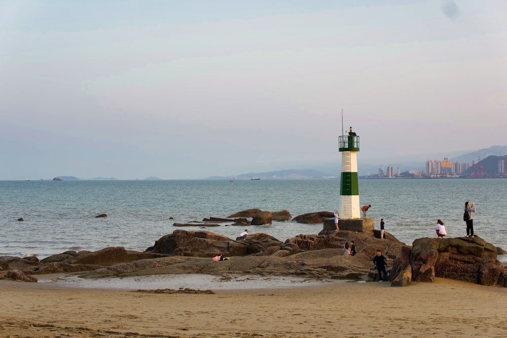 昼間の茶色の岩場の海岸に白と黒の灯台