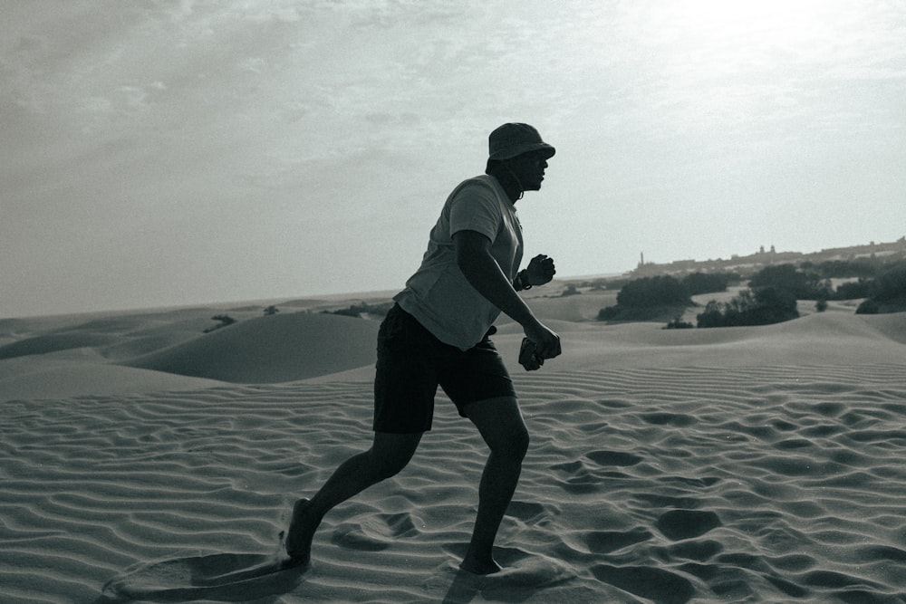 man in white shirt and black shorts walking on beach during daytime