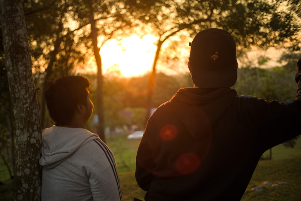 man and woman sitting on grass field during sunset