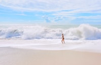 person in black shorts walking on seashore during daytime