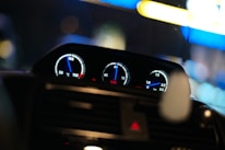 Close-up of hands using diagnostic tools on a vehicle dashboard with blue lighting.