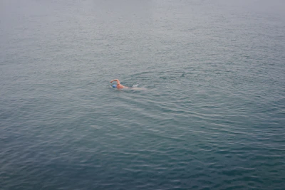 A beginner swimmer receiving gentle guidance from an instructor in a calm pool.