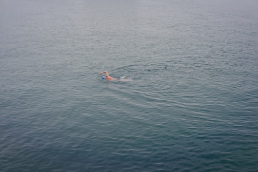Close-up of a swimmer mid-stroke creating ripples in the water.