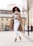 woman in white long sleeve shirt and white pants standing on road during daytime