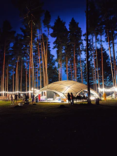 A family enjoying a cozy camp inside a spacious dome tent surrounded by lush forest.