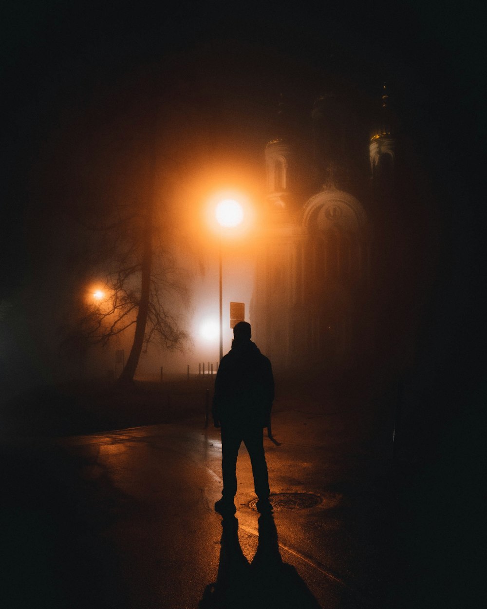 man in black jacket standing on road during night time