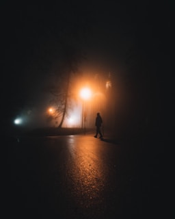 A shadowy figure walking down a foggy street at night, evoking suspense.