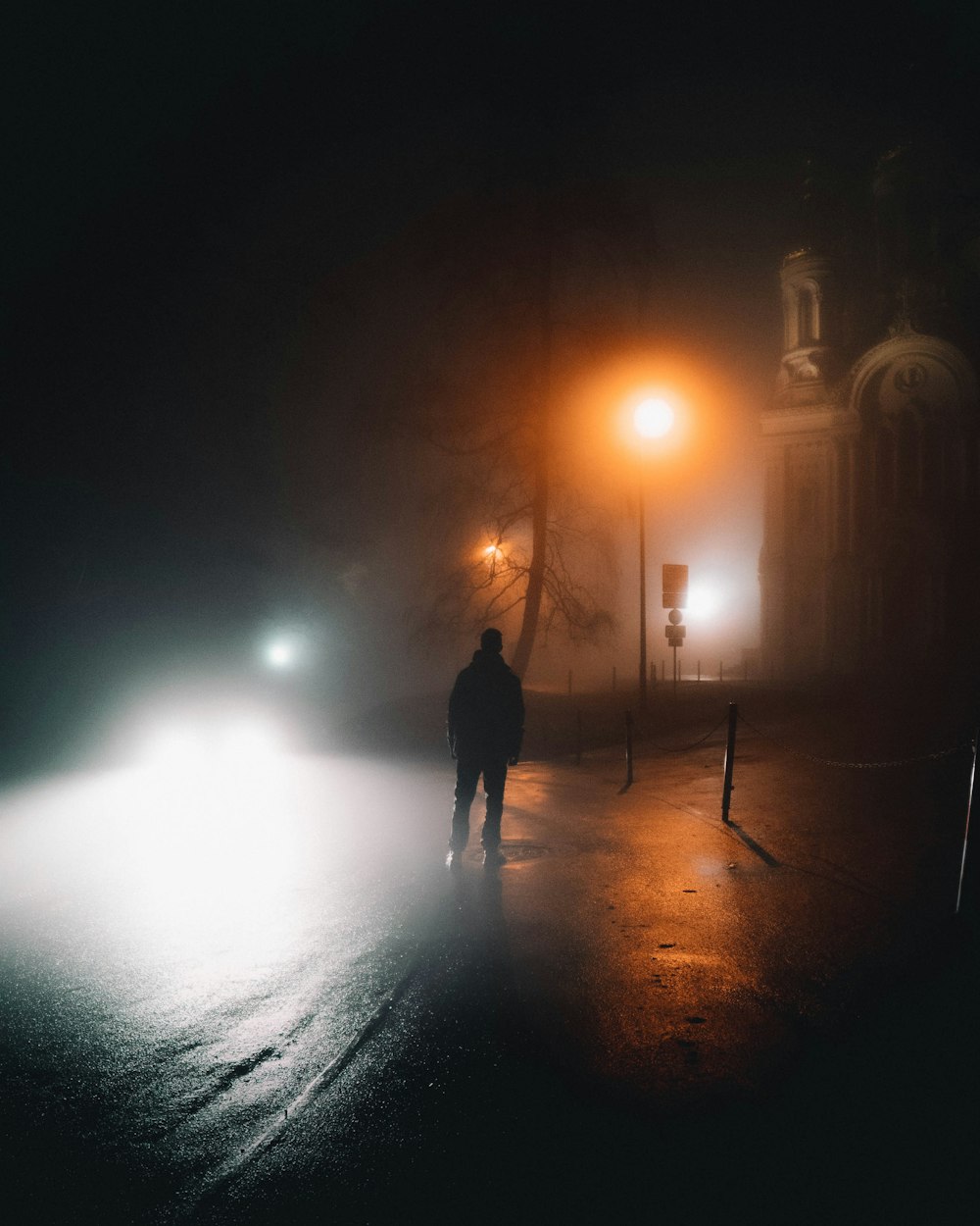 man in black jacket walking on street during night time