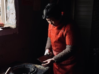 A caregiver helping a senior woman with light household tasks in a warm kitchen.