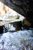 Close-up of mineral-rich thermal water flowing over smooth rocks in a forest setting.
