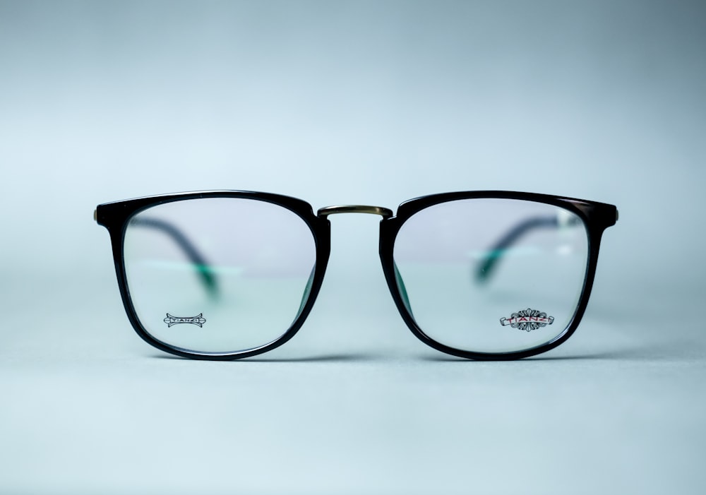 occhiali con cornice nera su superficie bianca