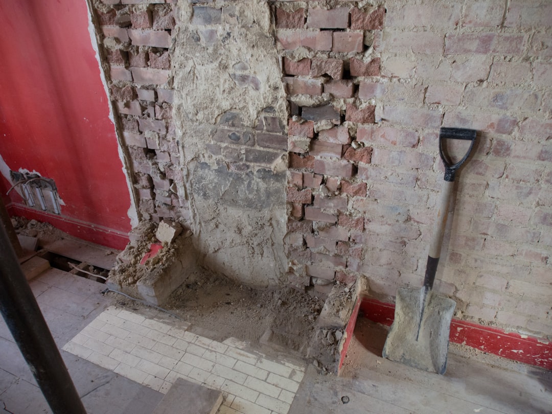 black shovel leaning on brown brick wall